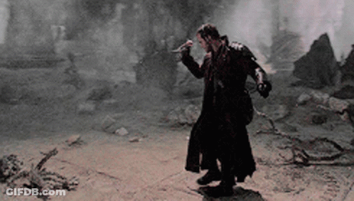 A Man In A Long Black Coat Is Holding A Sword GIF