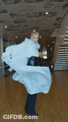 A Man In A Long White Coat And Black Pants Is Dancing GIF