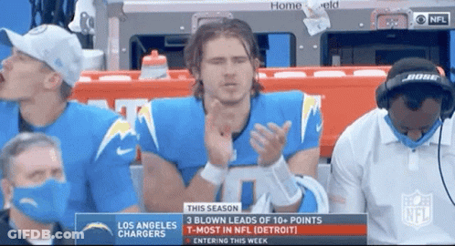 A Man In A Los Angeles Chargers Jersey Is Applauding While Watching A Football Game . GIF
