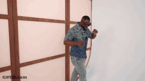 A Man In A Louis Vuitton Shirt Is Standing In Front Of A Wooden Wall GIF