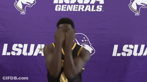 A Man In A Lsua Jersey Smiles In Front Of A Purple Backdrop GIF