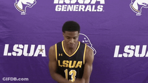 A Man In A Lsua Jersey Stands In Front Of A Purple Banner GIF