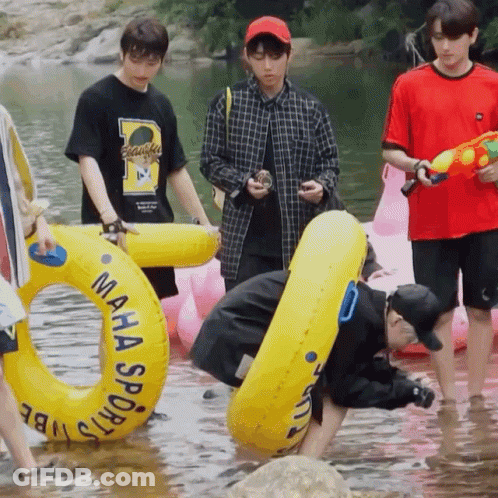 A Man In A Maha Sports Shirt Is Kneeling In The Water Holding A Water Gun GIF