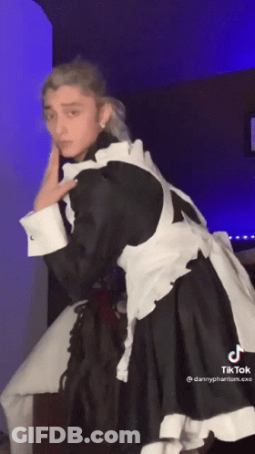 A Man In A Maid Costume Is Dancing In A Room With A Blue Light Behind Him . GIF