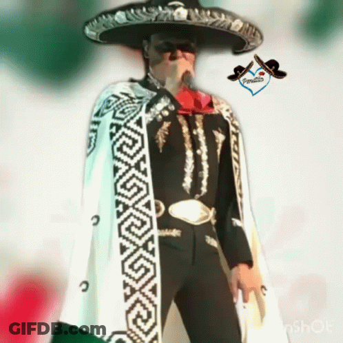 A Man In A Mariachi Outfit Is Holding A Microphone And Wearing A Sombrero GIF