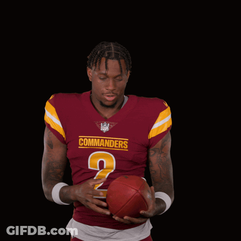 A Man In A Maroon Commanders Jersey Holds A Football GIF