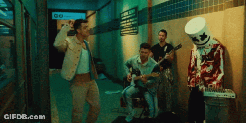 A Man In A Marshmallow Costume Plays A Guitar In A Dark Hallway GIF