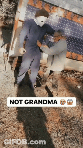 A Man In A Mask Is Being Helped By An Elderly Woman With The Words Not Grandma Below Him GIF