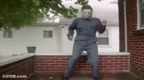 A Man In A Mask Is Dancing On A Porch In Front Of A Brick House . GIF