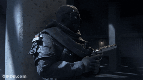 A Man In A Mask Is Holding A Gun With The Letter T On The Barrel GIF