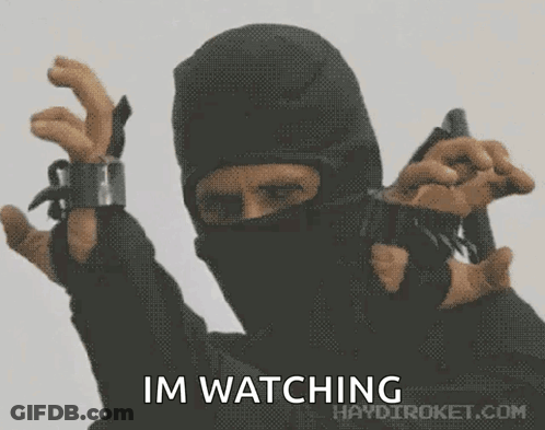 A Man In A Mask Is Holding A Gun With The Words Im Watching Written Below Him GIF