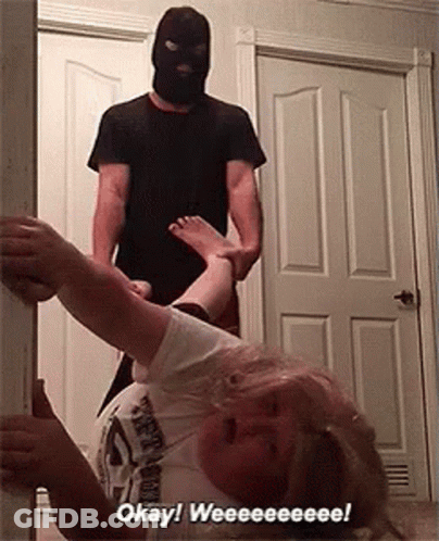 A Man In A Mask Is Holding A Woman 'S Leg In A Doorway And Says Okay ! Weeeee ! GIF