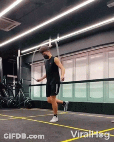 A Man In A Mask Is Jumping A Jump Rope In A Gym . GIF