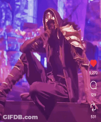A Man In A Mask Is Singing Into A Microphone On Stage GIF