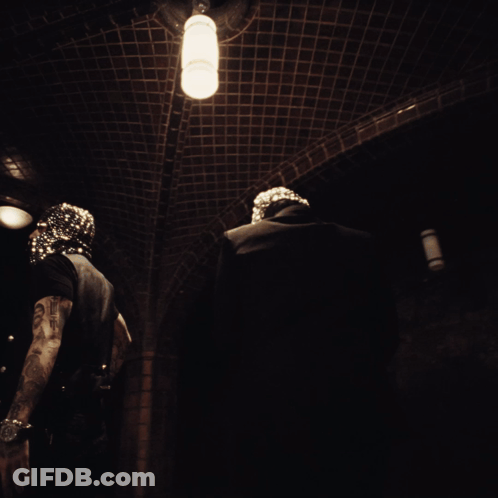 A Man In A Mask Is Standing In A Dark Hallway GIF