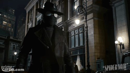 A Man In A Mask Is Standing In Front Of A Building That Says Spider-Man On It GIF