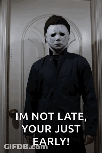 A Man In A Mask Is Standing In Front Of A Door And Says " Im Not Late Your Just Early " GIF