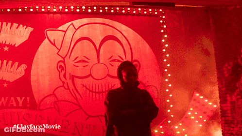 A Man In A Mask Is Standing In Front Of A Sign That Says ' Lust ' On It GIF