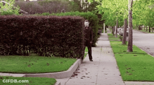A Man In A Mask Is Walking Down The Sidewalk GIF