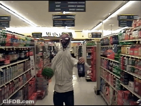A Man In A Mask Is Walking Through A Grocery Store Aisle With A Sign That Says Meats GIF