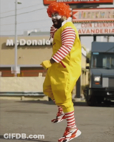 A Man In A Mcdonald 'S Costume Is Jumping In Front Of A Mcdonald 'S GIF