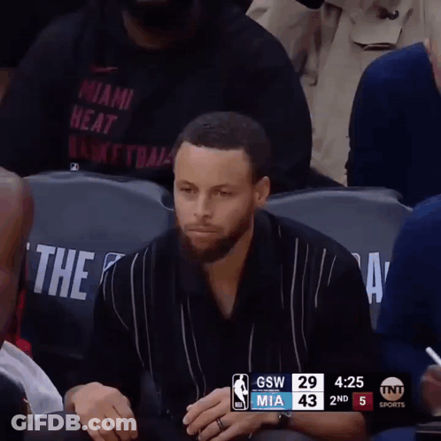 A Man In A Miami Heat Shirt Sits In The Stands GIF