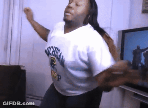 A Man In A Michigan Shirt Is Dancing In A Living Room GIF