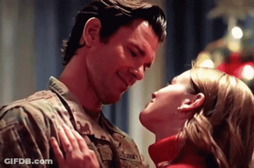 Military Couple Kissing In Front Of Christmas Tree GIF
