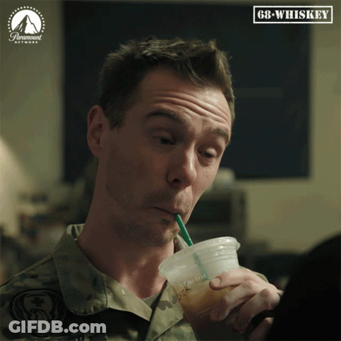 A Man In A Military Uniform Drinks Through A Straw From A Plastic Cup With Gb-Whiskey Written On The Bottom GIF