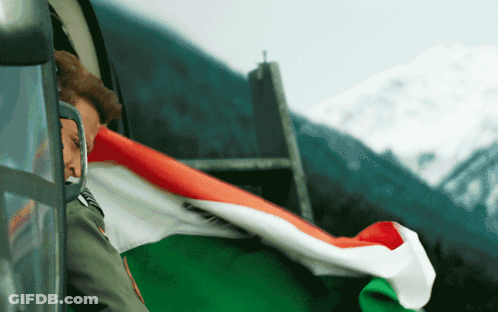A Man In A Military Uniform Is Holding A Flag In Front Of A Mountain GIF