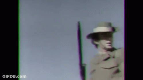A Man In A Military Uniform Is Holding A Rifle Against A Blue Sky . GIF
