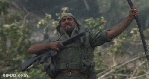 A Man In A Military Uniform Is Holding A Rifle With His Arms Outstretched GIF