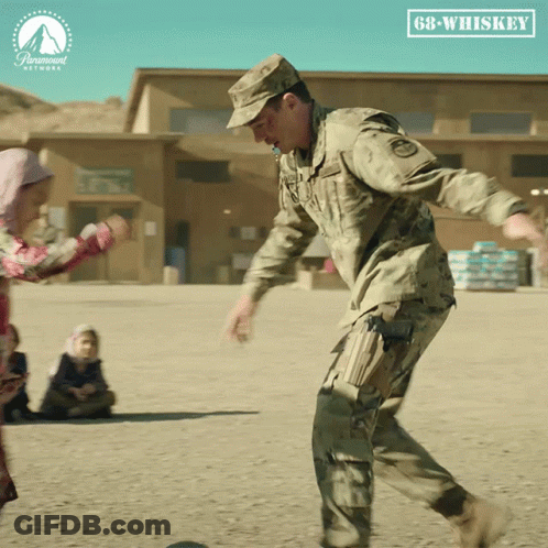 Man In Military Uniform Kicking Ball In Front Of Paramount Sign GIF