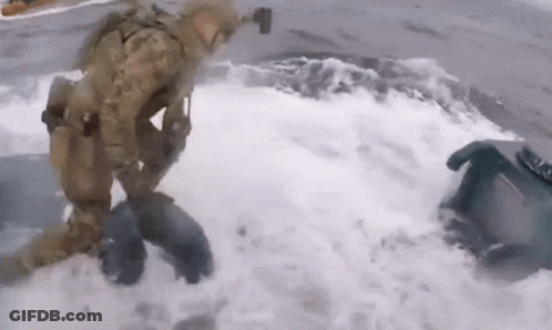 A Man In A Military Uniform Is Kneeling In The Water . GIF