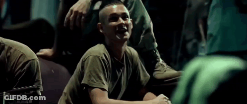 A Man In A Military Uniform Is Laughing While Sitting On The Ground . GIF
