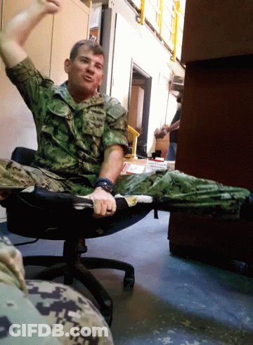 A Man In A Military Uniform Is Sitting In A Chair With His Arms In The Air GIF