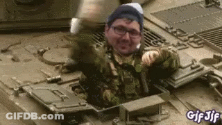 A Man In A Military Uniform Is Sitting In The Back Of A Military Vehicle . GIF