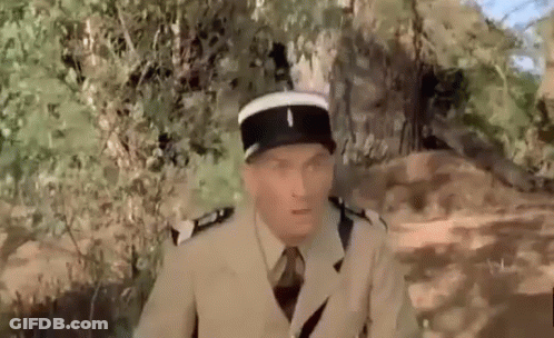 A Man In A Military Uniform Is Sitting In The Woods . GIF