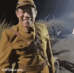 A Man In A Military Uniform Is Smiling While Standing In A Field . GIF