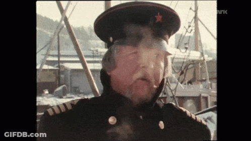 A Man In A Military Uniform Is Smoking A Cigarette While Wearing A Hat With A Star On It . GIF