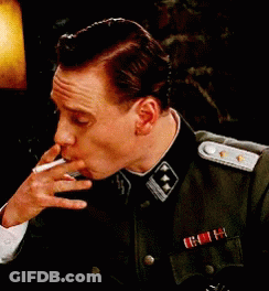 A Man In A Military Uniform Is Smoking A Cigarette While Wearing A Medal GIF