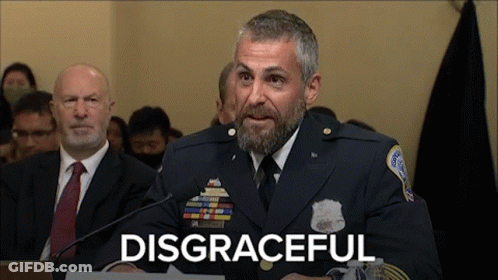 A Man In A Military Uniform Is Speaking Into A Microphone With The Word Disgraceful Written Below Him GIF