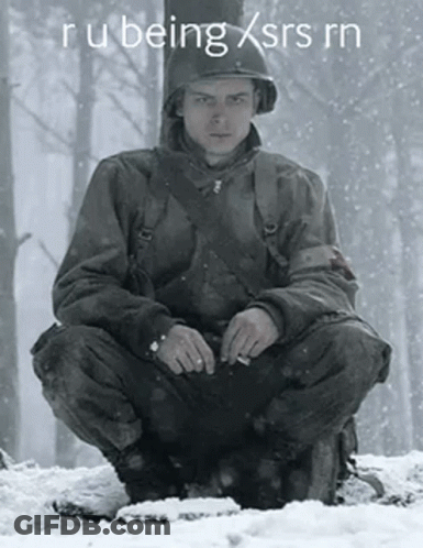 A Man In A Military Uniform Is Squatting In The Snow GIF