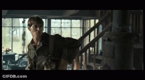 A Man In A Military Uniform Is Standing In A Dark Room GIF