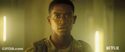 A Man In A Military Uniform Is Standing In A Dark Room With A Netflix Logo In The Corner . GIF