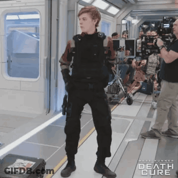 A Man In A Military Uniform Is Standing In A Room With The Words Death Cure On The Bottom GIF