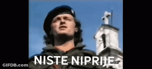 A Man In A Military Uniform Is Standing In Front Of A Church With The Words " Niste Niprive " On The Bottom Right GIF