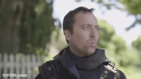 A Man In A Military Uniform Is Standing In Front Of A Fence . GIF