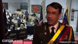 A Man In A Military Uniform Is Standing In Front Of A Group Of People In A Room . GIF