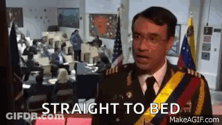 A Man In A Military Uniform Is Standing In Front Of A Group Of People In An Office . GIF